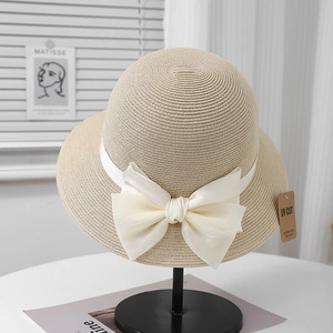 Détail d'un chapeau de paille beige avec ruban en satin blanc et étiquette anti-UV