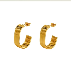 Macro detail of gold C-shaped earrings featuring a vintage layered wave texture finish