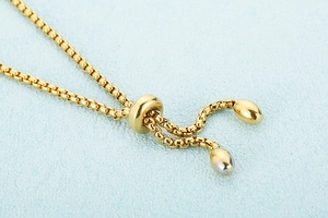 Macro detail of the gold-plated snake chain adjustable sliding buckle with polished beads