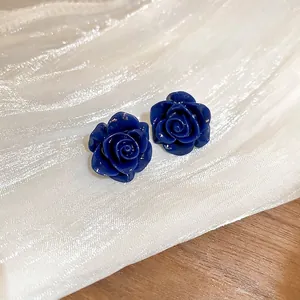 Élégantes boucles d'oreilles rose bleu marine sur soie blanche et fond bois