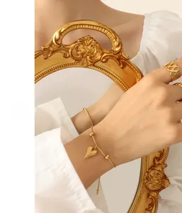 Detail of a gold heart pendant bracelet in stainless steel held with a vintage frame