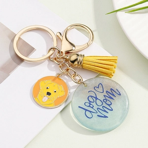 Close-up of a Dog Mom keychain featuring a yellow tassel and a glittery round tag
