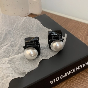 Detailed view of elegant black hair clips with large white pearls on a fashion book