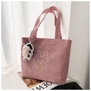 Detail of pink corduroy tote bag with rabbit embroidery and cow plush keychain