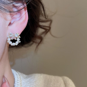 Detail view of a pearl wreath earring with a zircon bowknot on a model ear