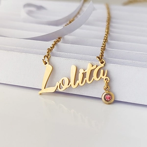 Close-up of golden custom Lolita name necklace featuring a pink birthstone pendant