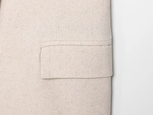 Dettaglio della trama in lino e delle cuciture della tasca sui pantaloncini beige