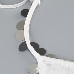 Detail of white fabric straps and shimmering silver sequins on a sexy evening dress