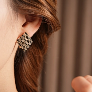 Gros plan sur des boucles d'oreilles dorées avec motif à carreaux noir et blanc