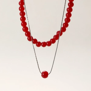 Close-up of double-layer necklace with red beads and delicate silver chain on white background