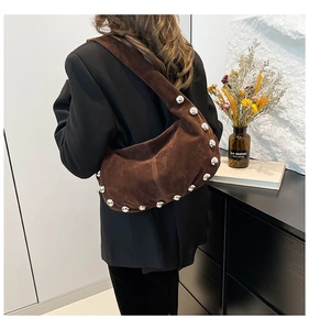 Dettaglio della borsa hobo in pelle scamosciata marrone con rivetti e tracolla larga