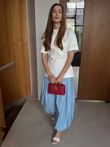 Detail of loose-fit blue harem trousers paired with a white cotton t-shirt for summer