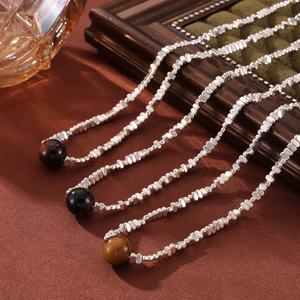 Tiger eye stone pendant necklace with silver faceted beads on brown silk background