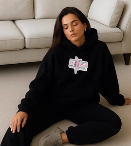 Detail of black oversized hoodie with pink ribbon money print in a street style look
