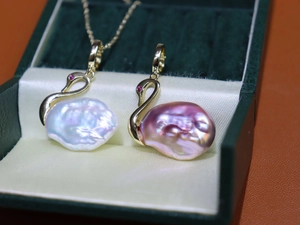 Gros plan détaillé de pendentifs cygnes en perles baroques blanches et lavande sur velours