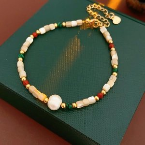 Détail macro d'un bracelet doré avec perles et coquillages sur une boîte en velours