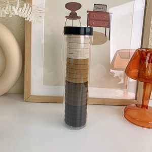 Close-up of 20 high-elastic seamless hair ties in gradient earthy tones in a clear tube
