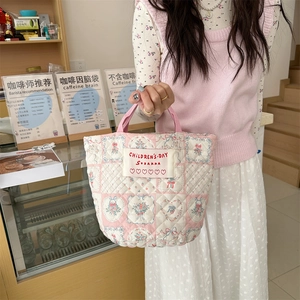 Détails de la texture matelassée du sac seau patchwork fleuri avec poignées roses