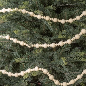 Natural wood bead garland with varying sizes hanging on festive green pine branches
