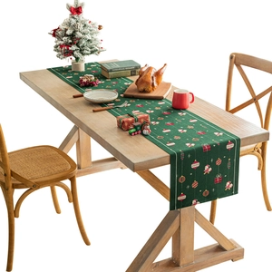 Runner da tavola natalizio verde con motivi di Babbo Natale su un tavolo da pranzo in legno