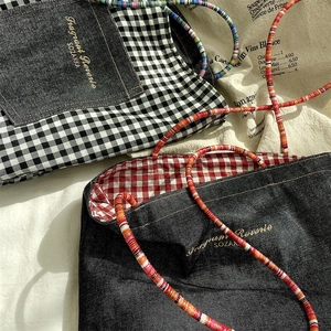 Detailed texture of denim canvas tote with colorful braided rope handles in sunlight