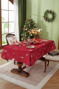 Close-up of red Christmas tablecloth with white snowflake and tree prints on a festive table