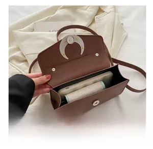 Sac bandoulière en cuir grainé marron montrant la capacité intérieure et le fermoir