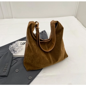 Detail of brown faux suede hobo bag with double shoulder straps on white bedding