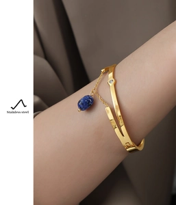 Macro detail of gold-plated stainless steel bracelet with blue oval stone and zircon