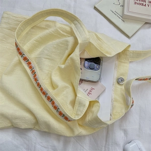 Macro view of floral embroidery on yellow tote bag with textured fabric and magnetic snap