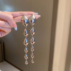 Detail of silver long drop earrings with cascading metallic leaf units being held by hand