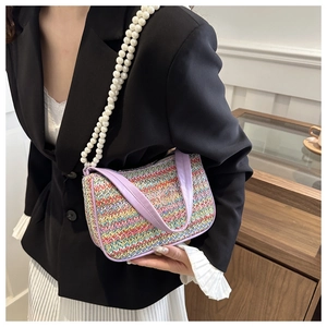 Close-up of rainbow straw woven bag with pearl strap and butterfly embroidery