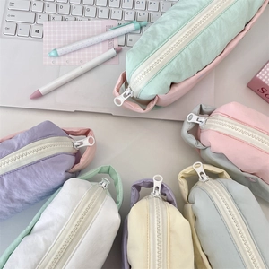 Flat lay of macaron-colored nylon pencil cases in mint, pink, and lilac with handles