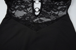 Detail eines schwarzen Kleides aus Blumenspitze mit Cut-Outs und silbernen Metallringen