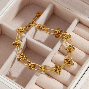 Detailed macro view of 18K gold knot bracelet with extension chain in a white jewelry box