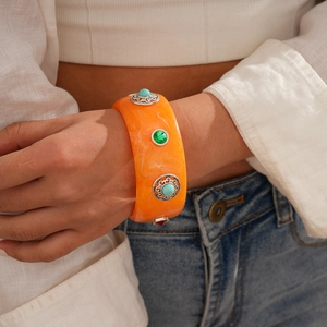 Detail of bohemian orange resin bangle with turquoise stones on model arm