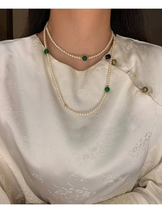 Detail of layered faux pearl necklace with green beads on a model in oriental style