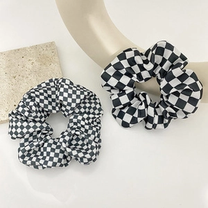 Detail view of two black and white checkerboard scrunchies made of soft fabric texture