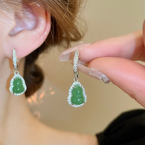 Macro detail of emerald green gourd earrings featuring silver-tone pave crystal settings