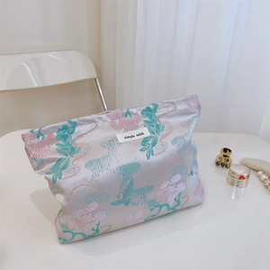 Detailaufnahme des rosa Kranich- und Kiefernmusters auf glatter Satin-Tasche