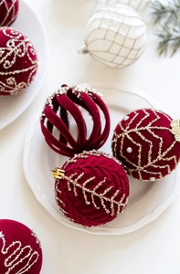 Gros plan de boules de Noël 8cm bordeaux floquées avec broderie dorée sur une assiette