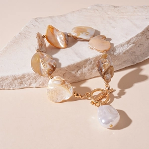 Detail of shell necklace with irregular amber beads, baroque pearl, and gold T-bar clasp
