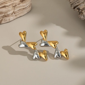 Close-up of gold and silver heart earrings with polished finish on a minimalist surface