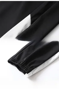 Detail view of black men's joggers with white side stripes and ribbed elastic cuffs