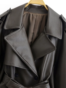 Détail de trench-coat marron foncé en simili cuir avec texture grainée et col à revers