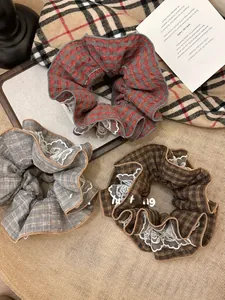 Detailed macro view of vintage red plaid scrunchies with white lace edges on textured surface