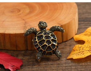 Macro detail of vintage sea turtle brooch showing black enamel shell and inlaid rhinestones