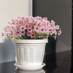 Detailed view of pink artificial violet flowers in a white textured plastic planter