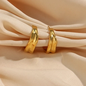 Close-up of golden C-shaped hoop earrings with metallic luster on silk background