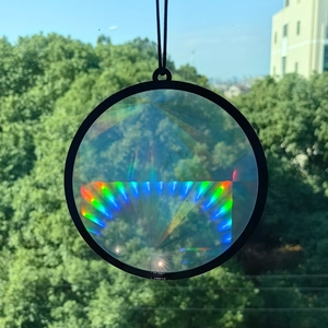 Close-up of a circular rainbow suncatcher prism with black frame creating light effects